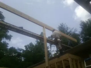 Carpenter setting a ridge beam over a new addition frame — Ice Dam Removal by Roofing Brothers in Iuka