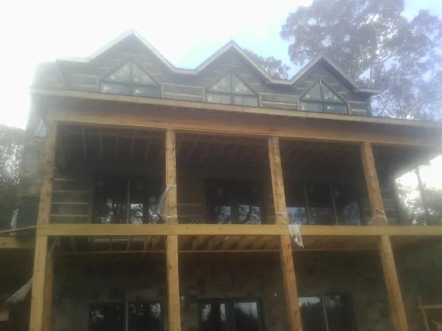 Dormers and porch framing on a large log home under construction — Roof Coating work by our crew in Iuka