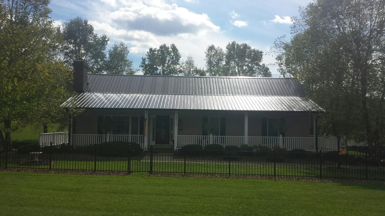Gray metal roof on a brick ranch with a full width front porch — Gutter Guard Installation work by our crew in Iuka