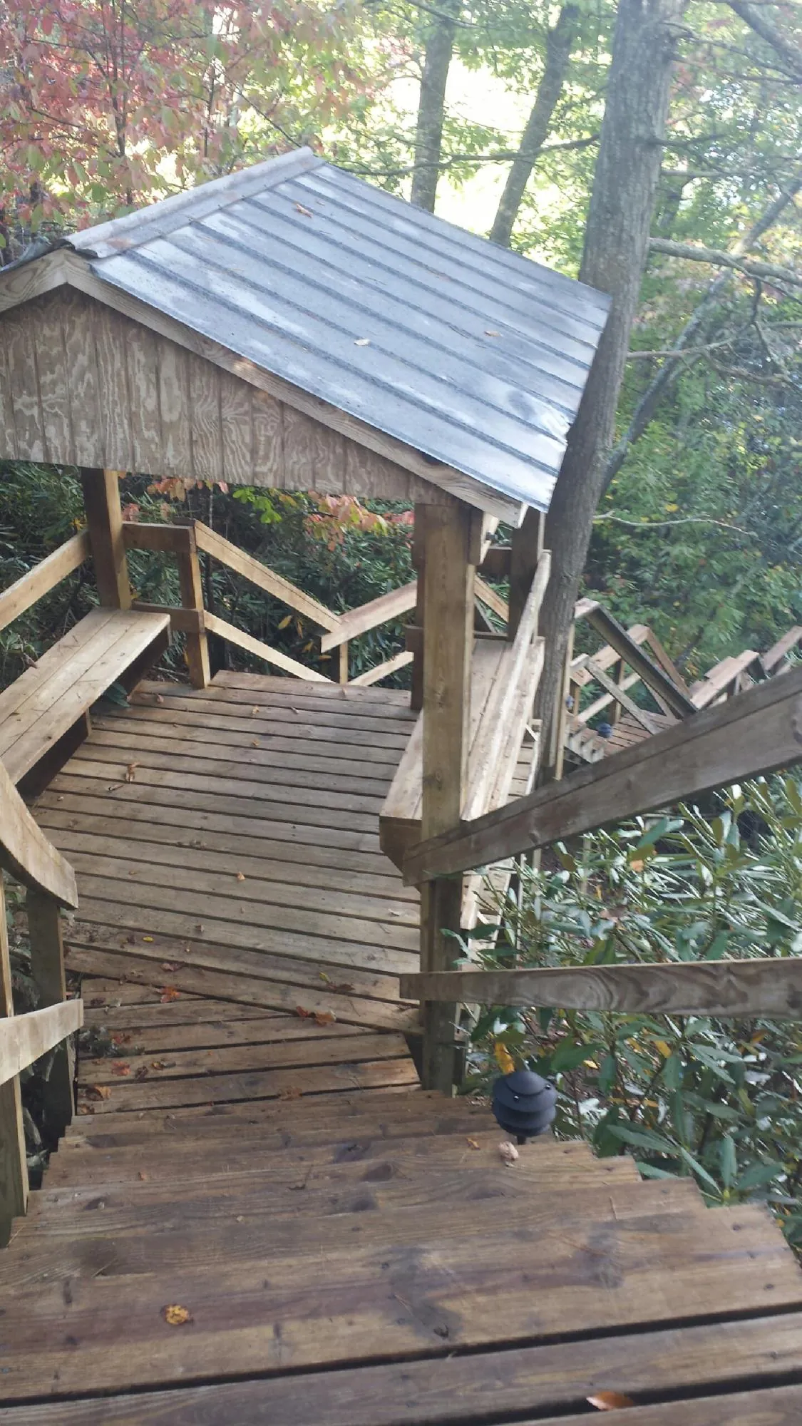 Metal roofed shelter over wooden steps on a wooded walkway — Skylight Repair & Installation work by our crew in Iuka