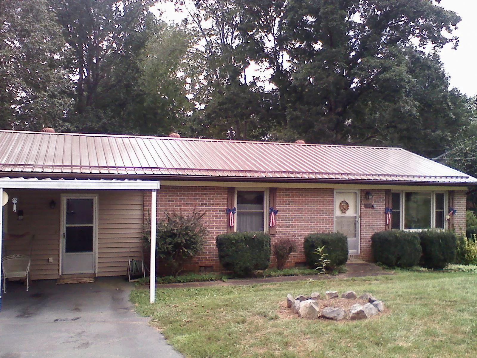 Bronze metal roof and carport on a brick ranch home — Roof Repair work by our crew in Iuka