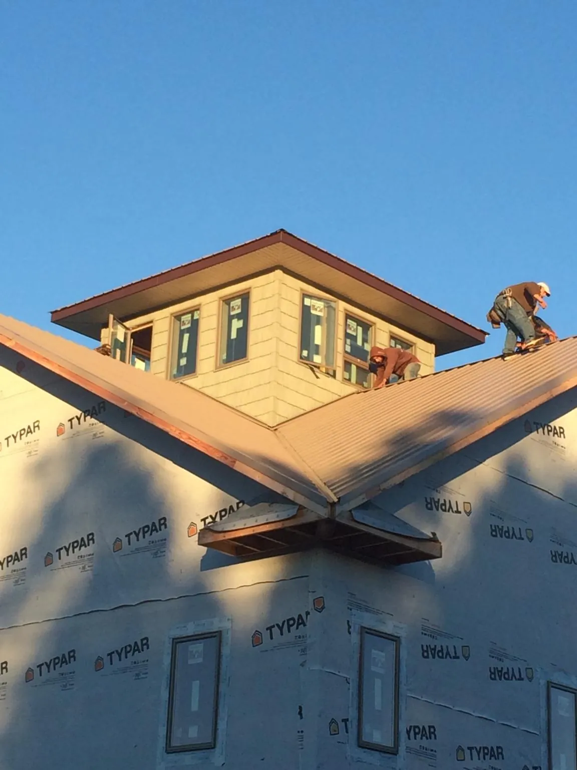 Roofers working around a rooftop cupola on a new metal roof at sunset — Roof Waterproofing in Iuka by Roofing Brothers